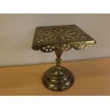 Late Victorian standing brass trivet on heavy stepped circular base with pierced square top, 9ins