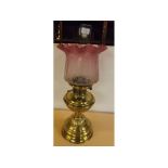 Victorian brass fonted oil lamp on a stepped circular base, etched cranberry shade, 22ins tall