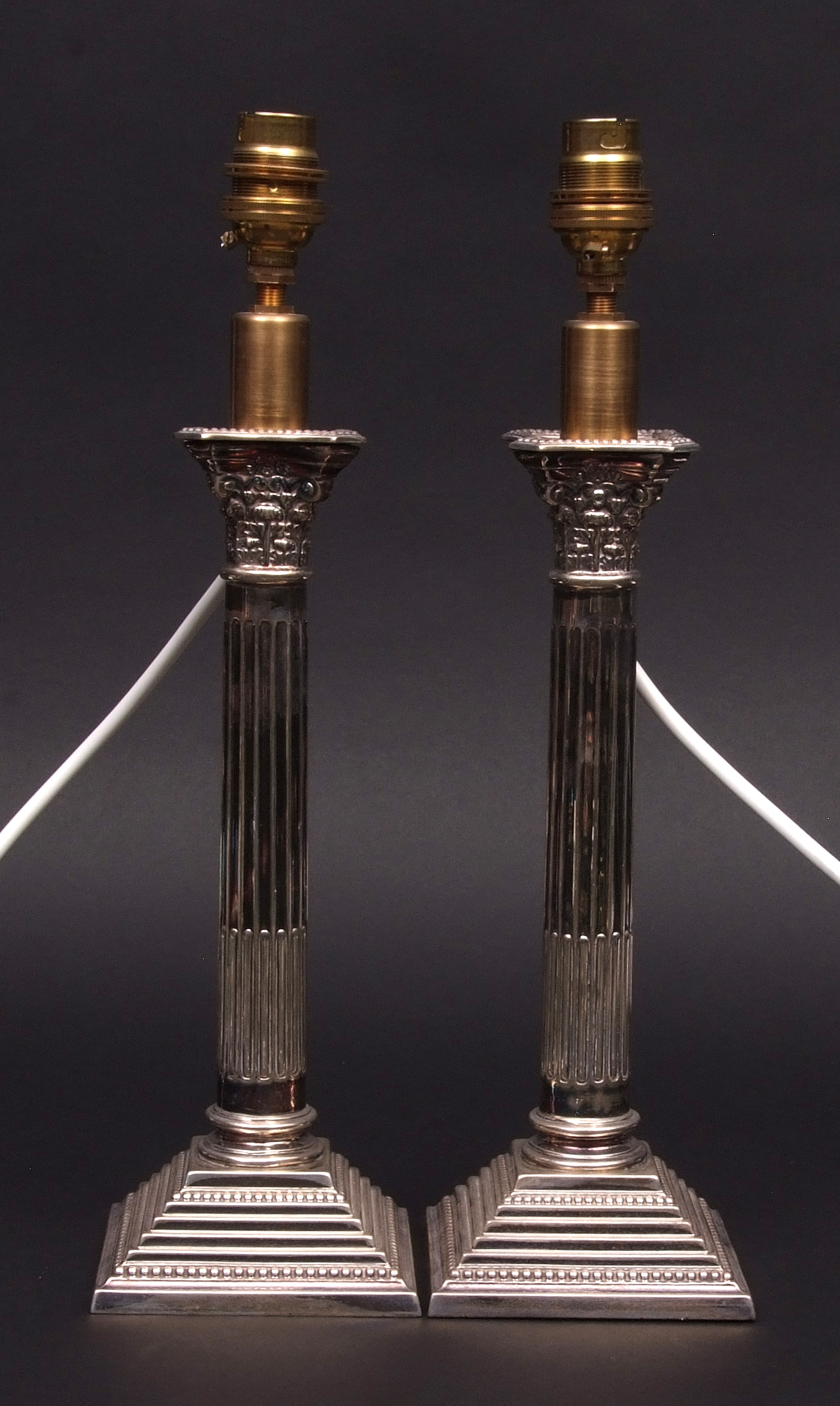 Two Elizabeth II single candlesticks each modelled as a Corinthian column on a stepped base (loaded)