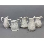 Five Portmeirion Parian ware jugs with raised decorative scenes, largest 5ins tall