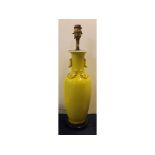 Oriental yellow glazed oil lamp with raised decoration and a turned wooden base, 17ins tall