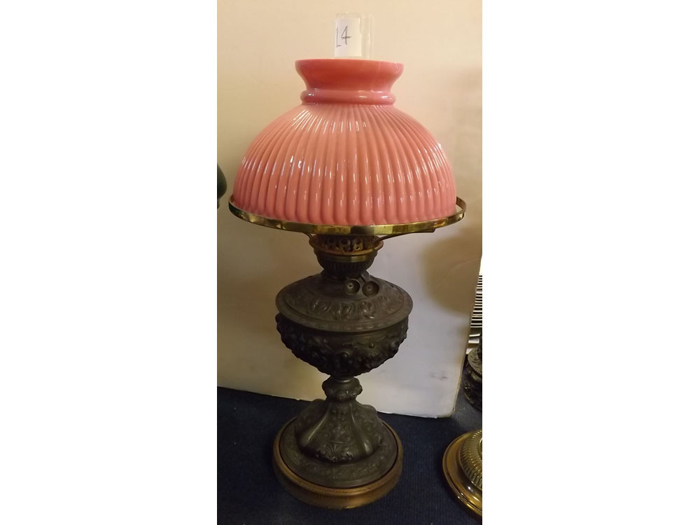 Cast pewter oil lamp with embossed decoration on a turned circular base, ribbed cranberry shade,