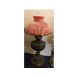 Cast pewter oil lamp with embossed decoration on a turned circular base, ribbed cranberry shade,