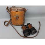 Leather cased pair of early 20th century binoculars in stove enamel and stitched leather, 5ins tall,