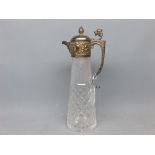 Cut glass and silver plated mounted claret jug with shaped handle, gryphon finial, impressed putti