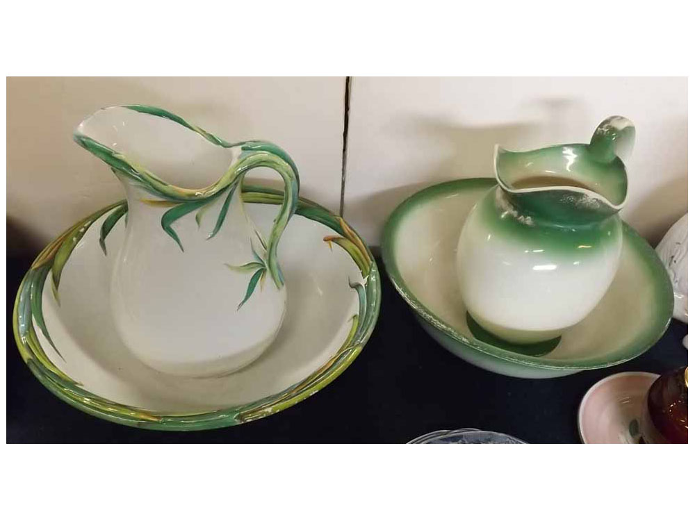 Two 19th century wash jugs and bowls, one with a raised leaf design and shaped handle, together with