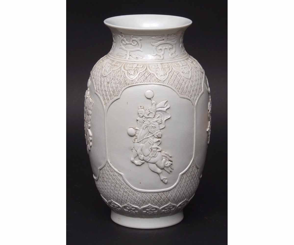 Chinese blanc de chine moulded vase with panels of equestrian figures within a lappet border,