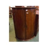 George III mahogany bow fronted corner cupboard fitted with two doors and enclosed three fixed