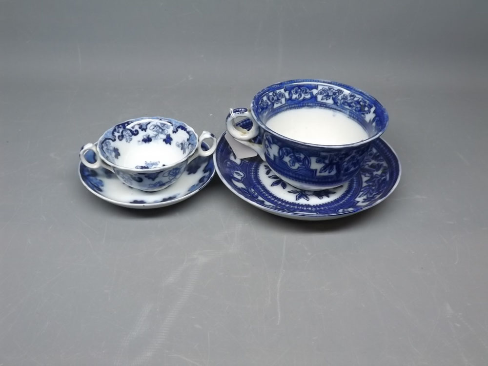 Large proportion blue and white cup and saucer with inscription and rim chips, together with a