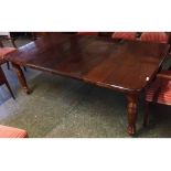 Edwardian mahogany extending dining table supported on four tapering cylindrical reeded legs and