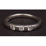 Modern precious metal and three stone diamond ring, the plain polished band set with three small