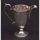 George V cream jug with cast and applied rim and handle to a faceted body and raised on a