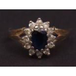 Modern sapphire and diamond cluster ring, the oval shaped faceted sapphire (7mm x 5mm approx),