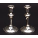 Two George V candlesticks, each with fixed sconces on inverted trumpet columns and spring circular