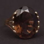 Modern 9ct gold and smoky quartz dress ring, the oval faceted quartz prong set in a pierced tapering