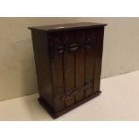 Arts & Crafts style oak table top single door cupboard with coppered hinges, raised on bun feet,