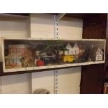 Modern cased and Perspex fronted village street scene with shops, figures and cars, 24ins x 8ins