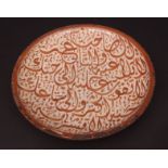 Middle Eastern earthenware footed dish with overall brown calligraphic decoration against a crazed