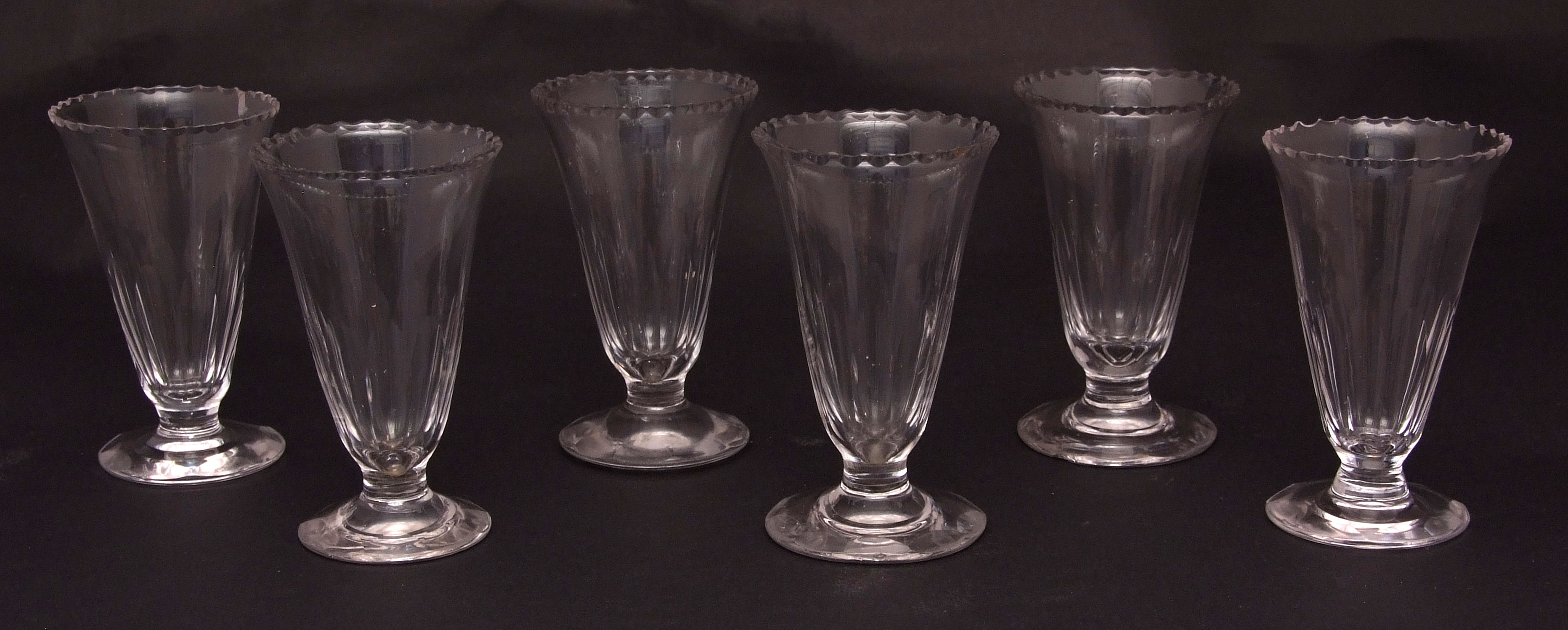 Six various jelly glasses, all with serrated rims, tapering faceted lower bodies on circular