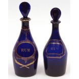 Two Bristol blue glass rum decanters, each with pear-shaped stoppers, gilded inscriptions and