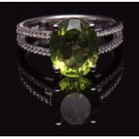 Modern precious metal peridot and diamond ring, the oval cut peridot (4.08cts approx), raised in a