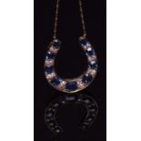 Early 20th century horseshoe shaped sapphire and diamond pendant, set with a row of graduated oval