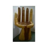 Rustic carved chair in the form of a hand, the palm as the seat and the fingers as the support,