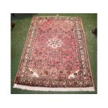 Modern wool rug with a coral ground, geometric design, central floral cream lozenge, multi-gulled