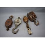 Box containing four vintage cast iron and wooden pulleys