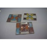 Three early 20th century decorative stained glass panels, two with central segmented square