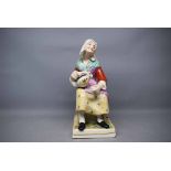 Reproduction Staffordshire large seated model of a lady with a water jug and beaker in her hand (a/