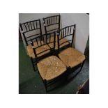 Set of four black painted bamboo style dining chairs with rush seats and open work backs on tapering