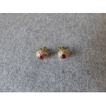 Pair of ruby and diamond cluster ear studs, the oval cabochon 5.5mmL x 4.4mmW, enclosed by ten
