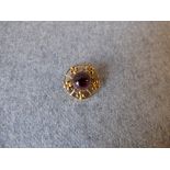 Garnet brooch with circular cabochon enclosed by flower head motif to a circular frame, 2.3cm