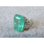 Large emerald and diamond ring, the step cut emerald 18.4mmL x 14.2mmW x 8mmD, with a trio of