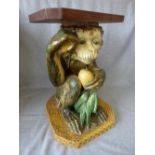 Large Majolica glazed monkey, crouched with a kernel in hand with associated wooden top 44H cm