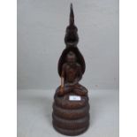 Carved wooden oriental figure of seated figure with carved dragon/serpent figure above, 38 cm H
