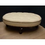 Contemporary oval footstool upholstered in cream fabric on ebonised style legs