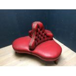 Victorian style conversation seat upholstered in red leather on turned mahogany legs to castors