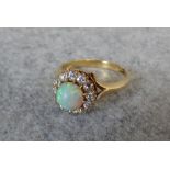Opal and diamond cluster ring, circa 1910, the round cabochon enclosed by twelve small old cuts