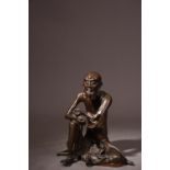 C17th Chinese bronze figure of an immortal, cast in seated position with his right hand resting on