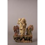 C18th/19th Chinese soapstone figure on a rockwork base, carrying a branch of fruiting peach over one