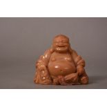 C18th Chinese soapstone figure of Budai, shown seated with the right knee raised, wearing long