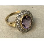 An amethyst and diamond cluster ring, 18 carat gold, Birmingham 1999, the oval cut stone enclosed by