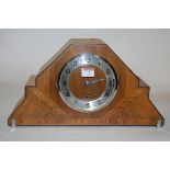 An Art Deco walnut cased mantel clock having a silvered dial with Arabic numerals