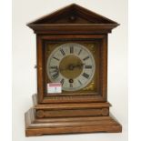 A late 19th century continental oak cased mantel clock having a silvered chapter ring with Roman