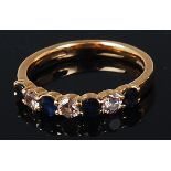 An 18ct gold, sapphire and diamond set band ring, arranged as four round cut sapphires,