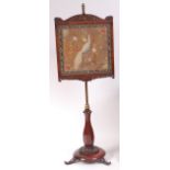 A William IV mahogany pedestal pole screen, the framed needlework panel on a lacquered brass column,