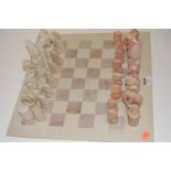 A set of carved soapstone chess pieces on soapstone chess board