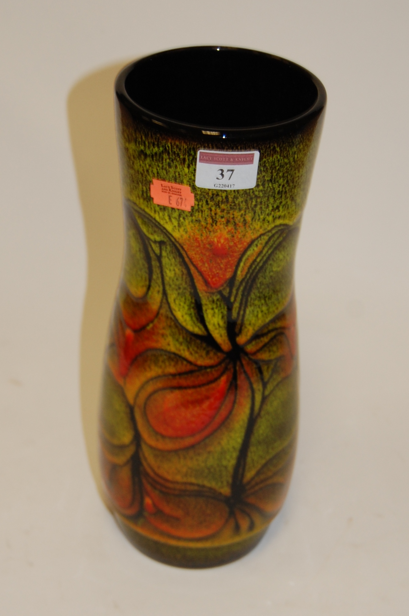 An early 20th century Poole pottery vase of cylindrical form brightly decorated with various